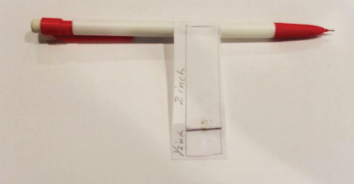 A pencil with a paper tag wrapped around it. The tag shows where a half inch is and 2 inches is.