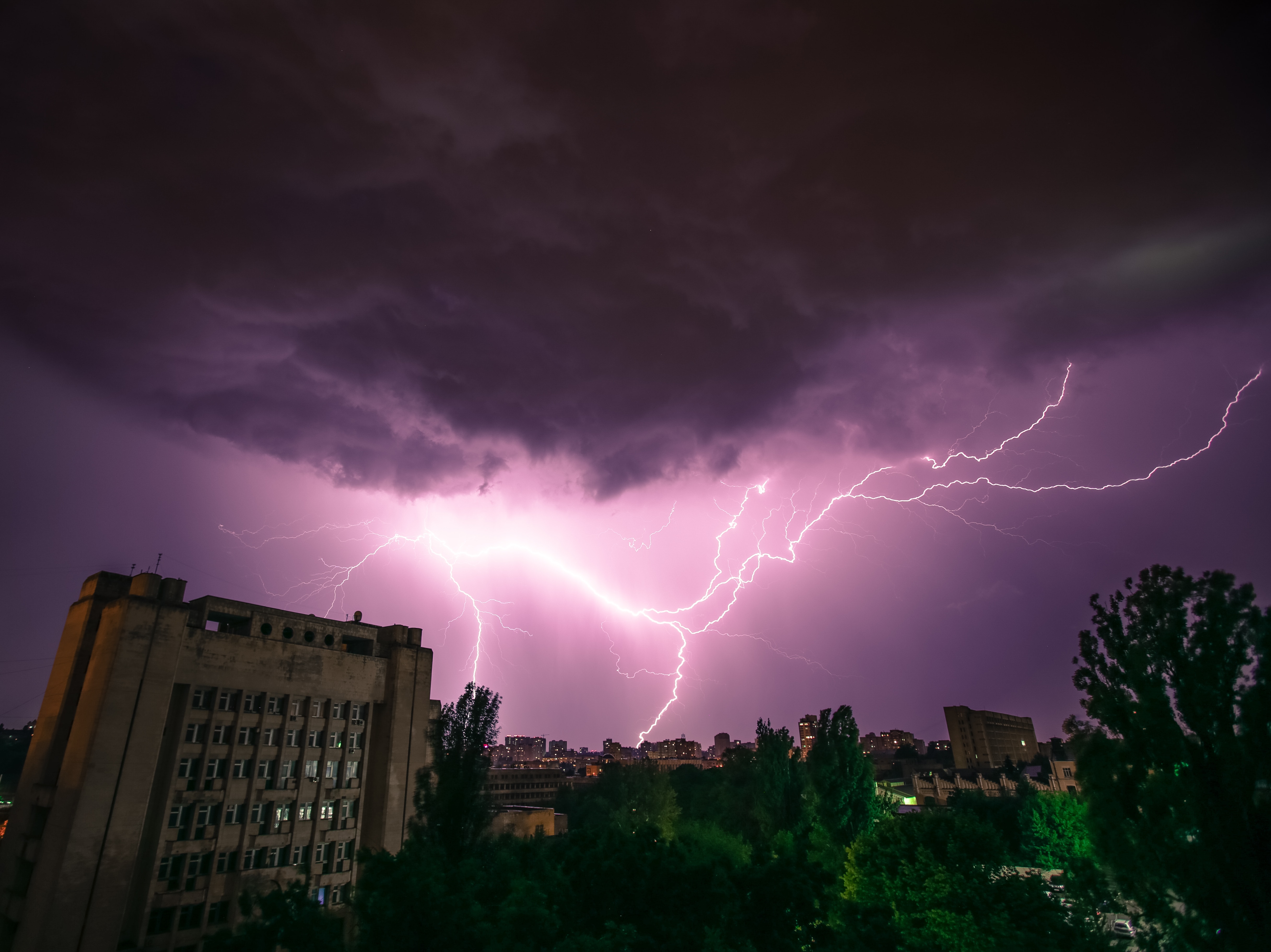 A photo of lightning flashing across the sky over a building