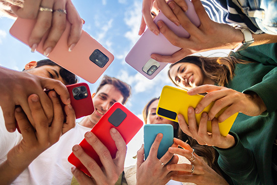 A group of people huddled in a circle, checking their phones