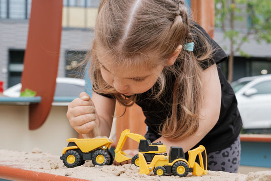 A child playing with trucks in a sandbox