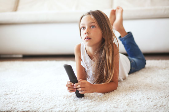 A young child lying on the floor, watching television