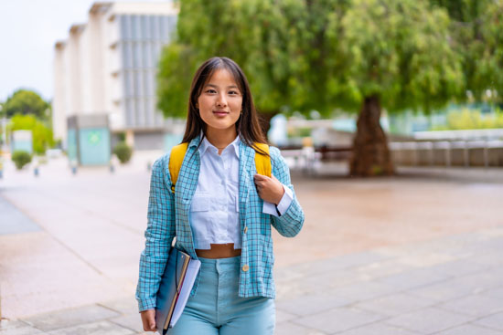 A person holding their books and smiling at the camera