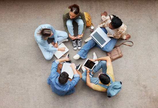 A group of students talking and sitting in a circle on the floor