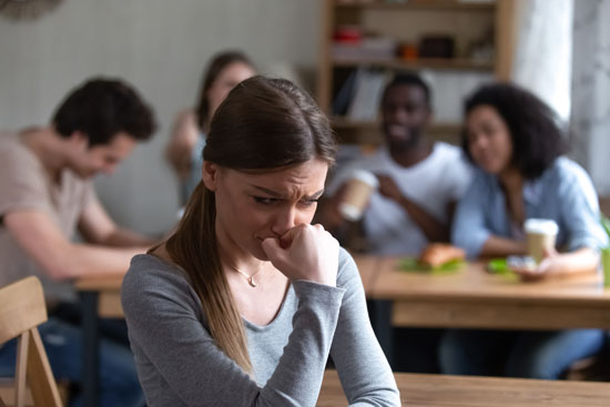 A person feeling lonely, separated from a group of their peers