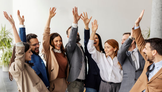 A group of coworkers, raising their hand in unison