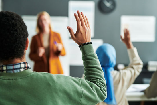 A young person raising their hand in class
