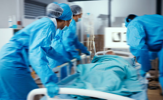 A group of hospital workers wheeling a patient into a room on a medical bed