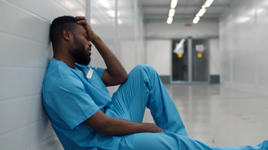 A person sitting in a hallway with their hand to their head