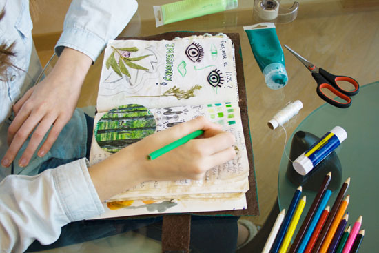 A teen drawing in a journal