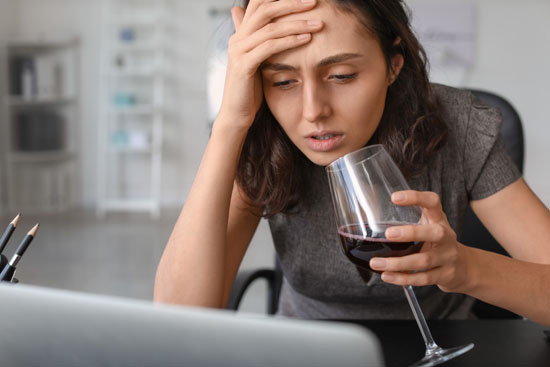A person looking unsettled and drinking alcohol