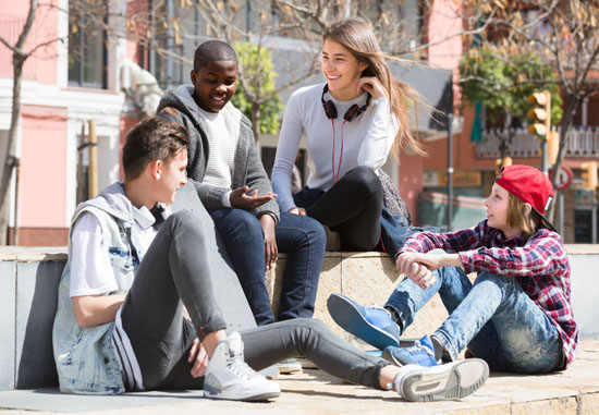 A group of teens sitting outside on a sunny day