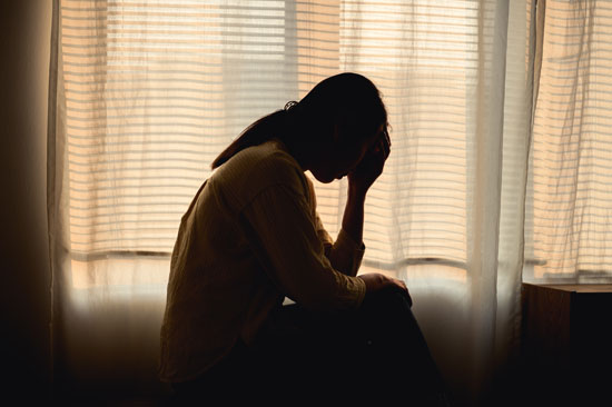 A person sitting upset alone in their room