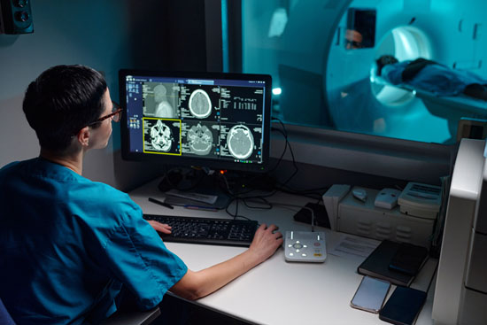 A picture of a technician reviewing brain scans of a patient getting an MRI