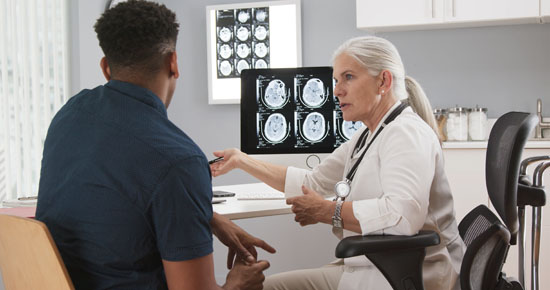 A picture of a doctor showing brain scans to a patient