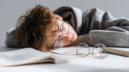 A picture of a student sleeping on books at a desk