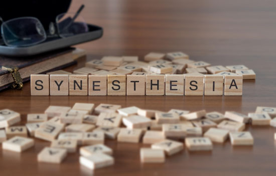 A picture of wooden blocks with letters on them, spelling 'synesthesia'