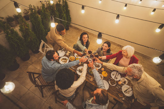 A picture of a group of people enjoying a meal under a string of lights