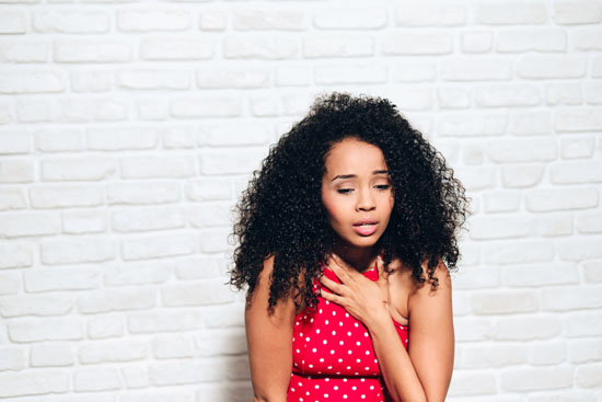 A young person leaning against a wall, having a panic attack