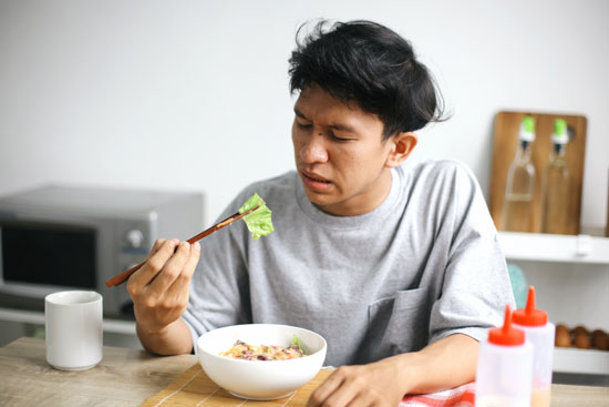 A picture of a young adult looking disgusted with their meal