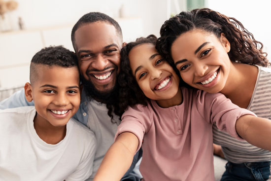 Two parents and two children, hugging and smiling at the camera