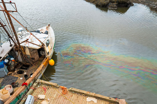 A picture of an oil slick in the water next to a boat