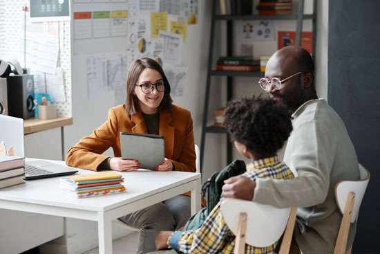 A picture of a parent and child meeting with a teacher at school