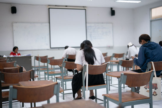 A picture of students taking tests, seated apart from each other