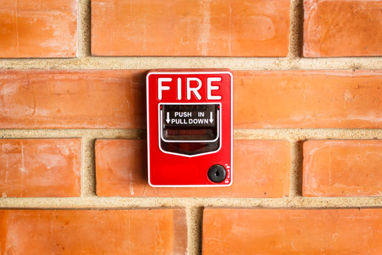 A picture of a fire alarm on a brick wall